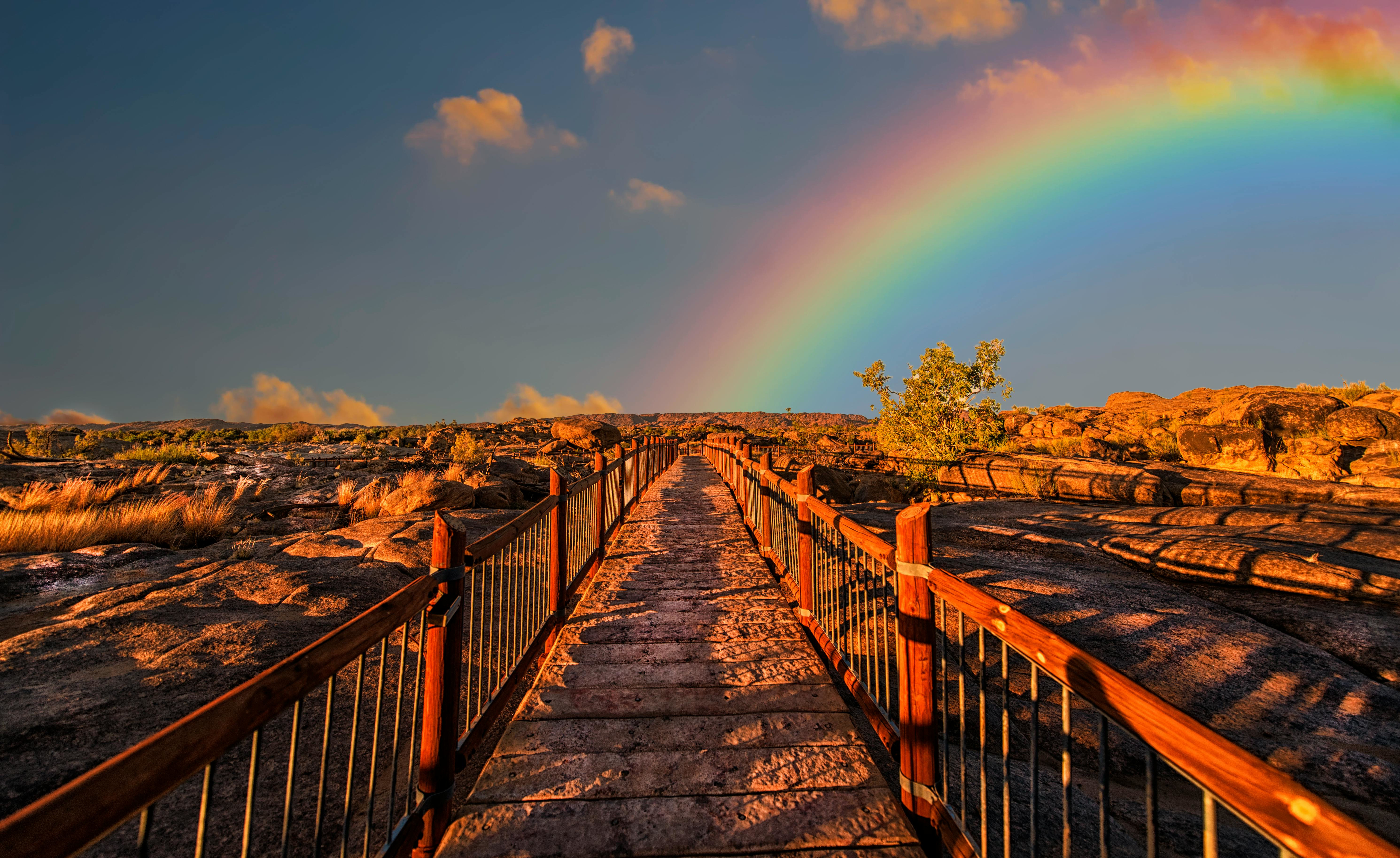 Kleurenfoto van een loopbrug met een regenboog