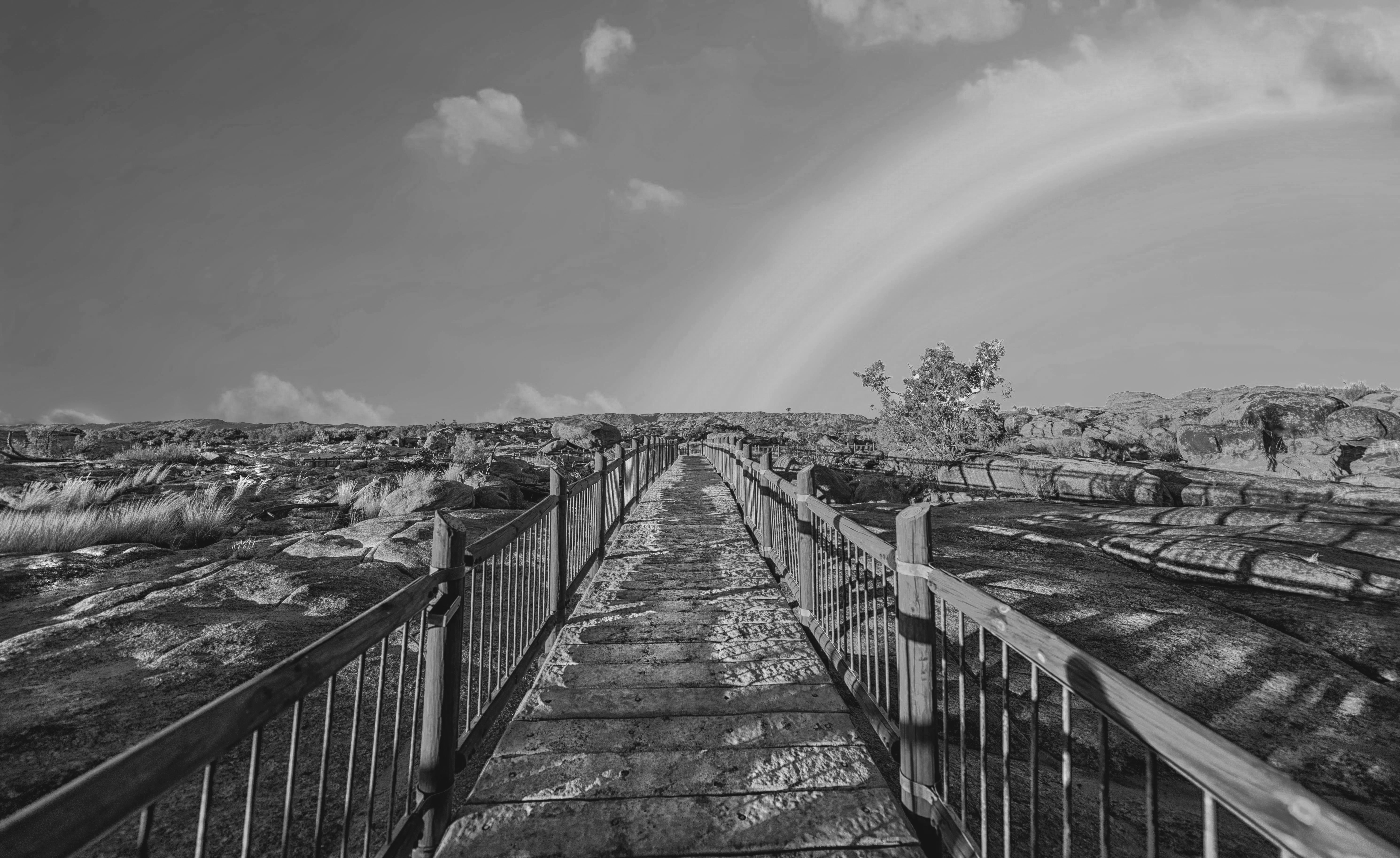 Zwart-wit-foto van een loopbrug met een regenboog